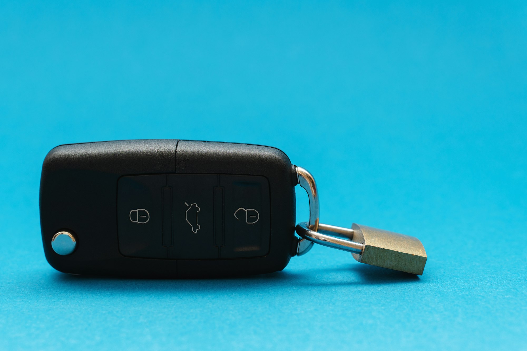 Padlock attached to a black car keys on blue background
